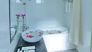 A modern bathroom with a large bathtub, a sink with a marble countertop, and a shower area.