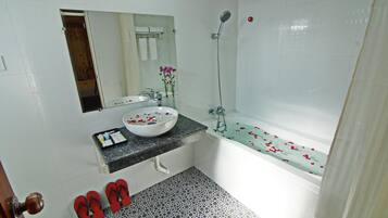 A bathroom with a white sink, a mirror, a shower, and a bathtub.