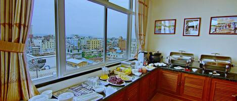 A buffet setup with a view of a cityscape through large windows.