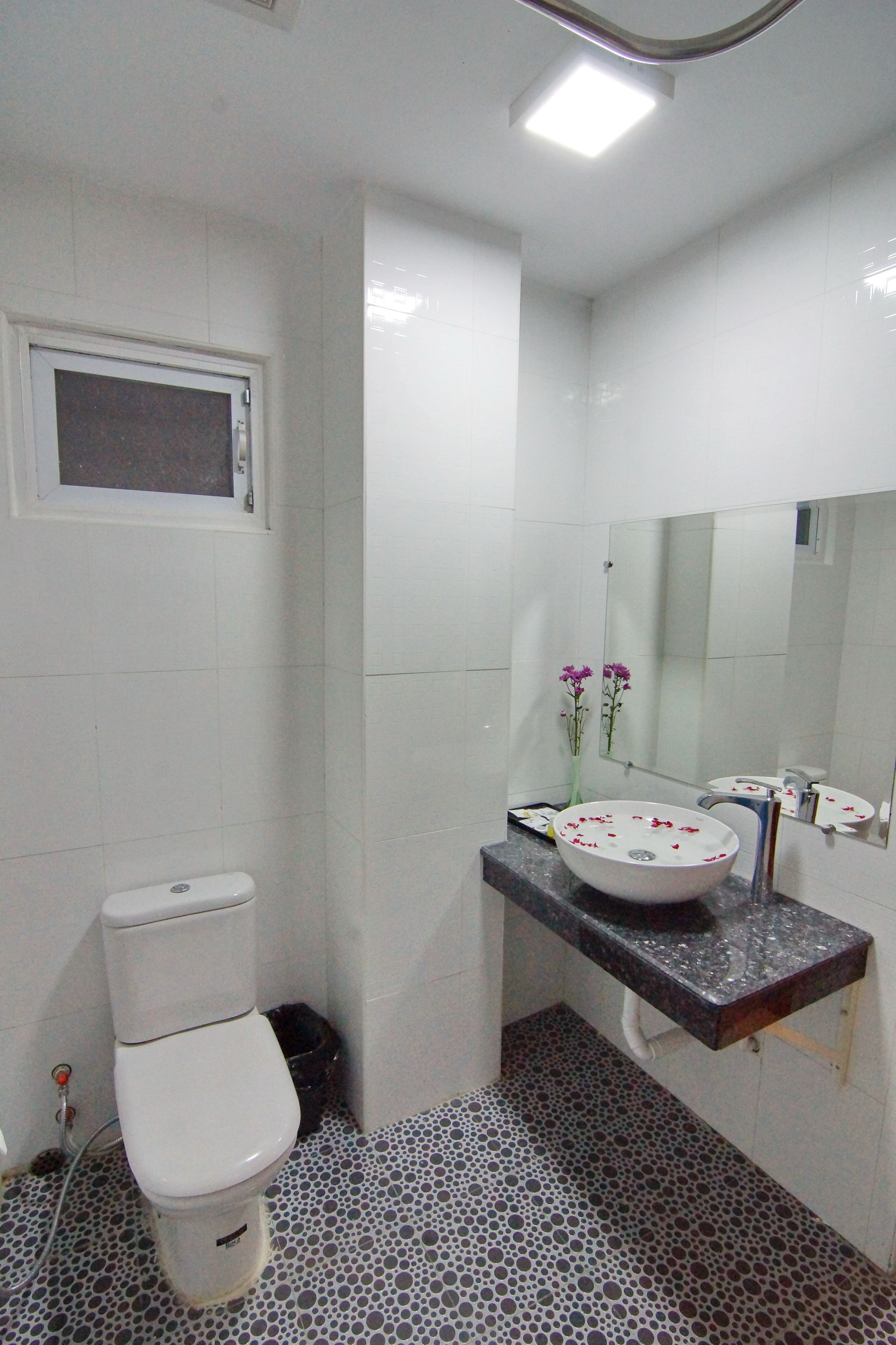 A bathroom with a toilet, a sink with a mirror, and a tiled floor.