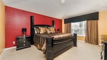 A bedroom with a bed, nightstands, a dresser, and a window with curtains.