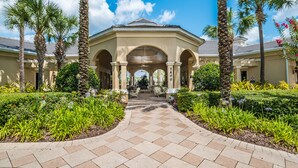 A covered walkway leading to a building with a tiled floor and palm trees. - Windsor Hills Resort Homes, Townhomes & Condos (Kissimmee)