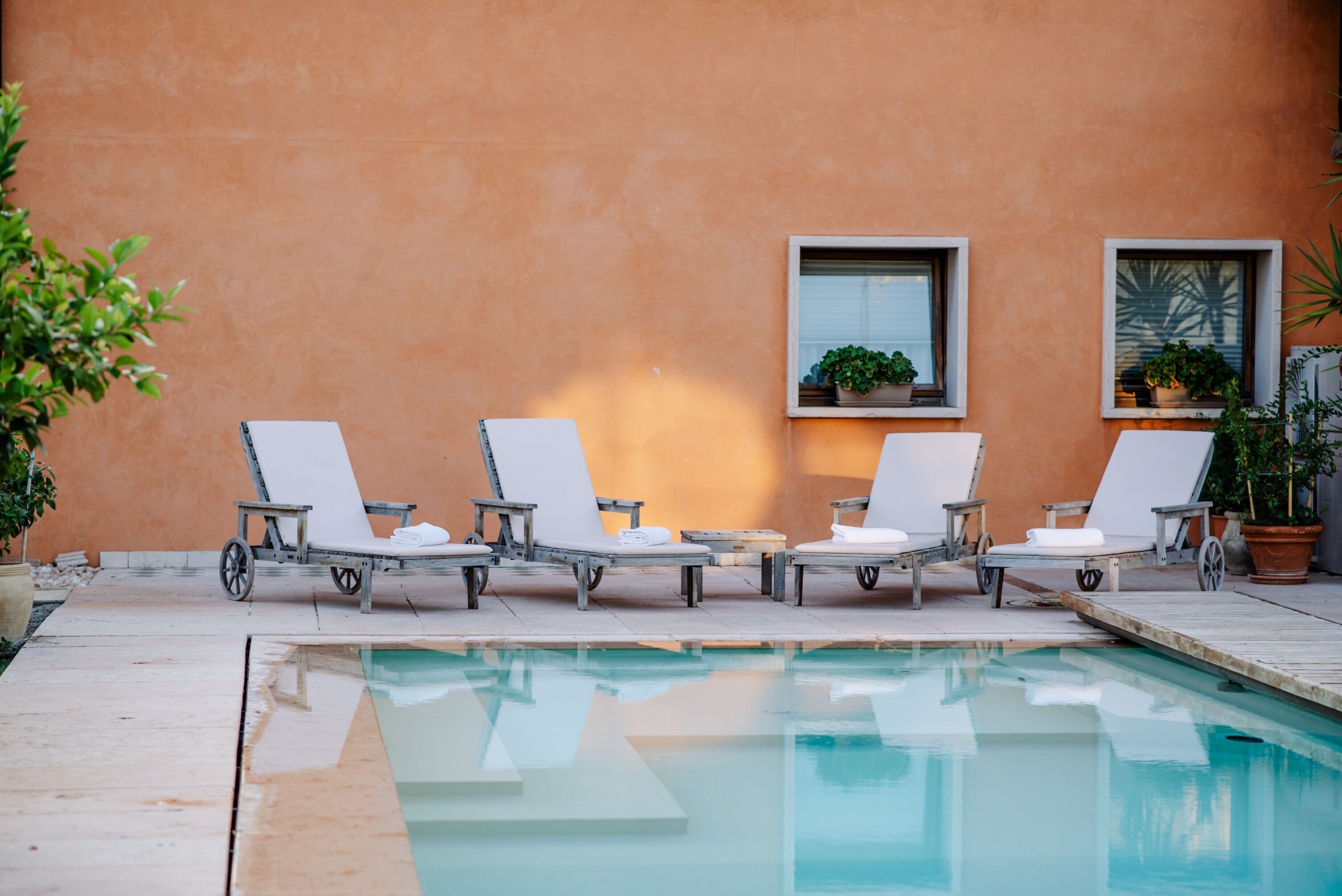 Un espace aménagé au bord de la piscine, avec des chaises longues, une petite table et des plantes en pot.
