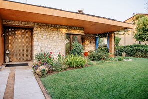 A modern house with a stone facade, a wooden door, and a well-maintained garden. - La dolce Vita (Montecchia di Crosara)