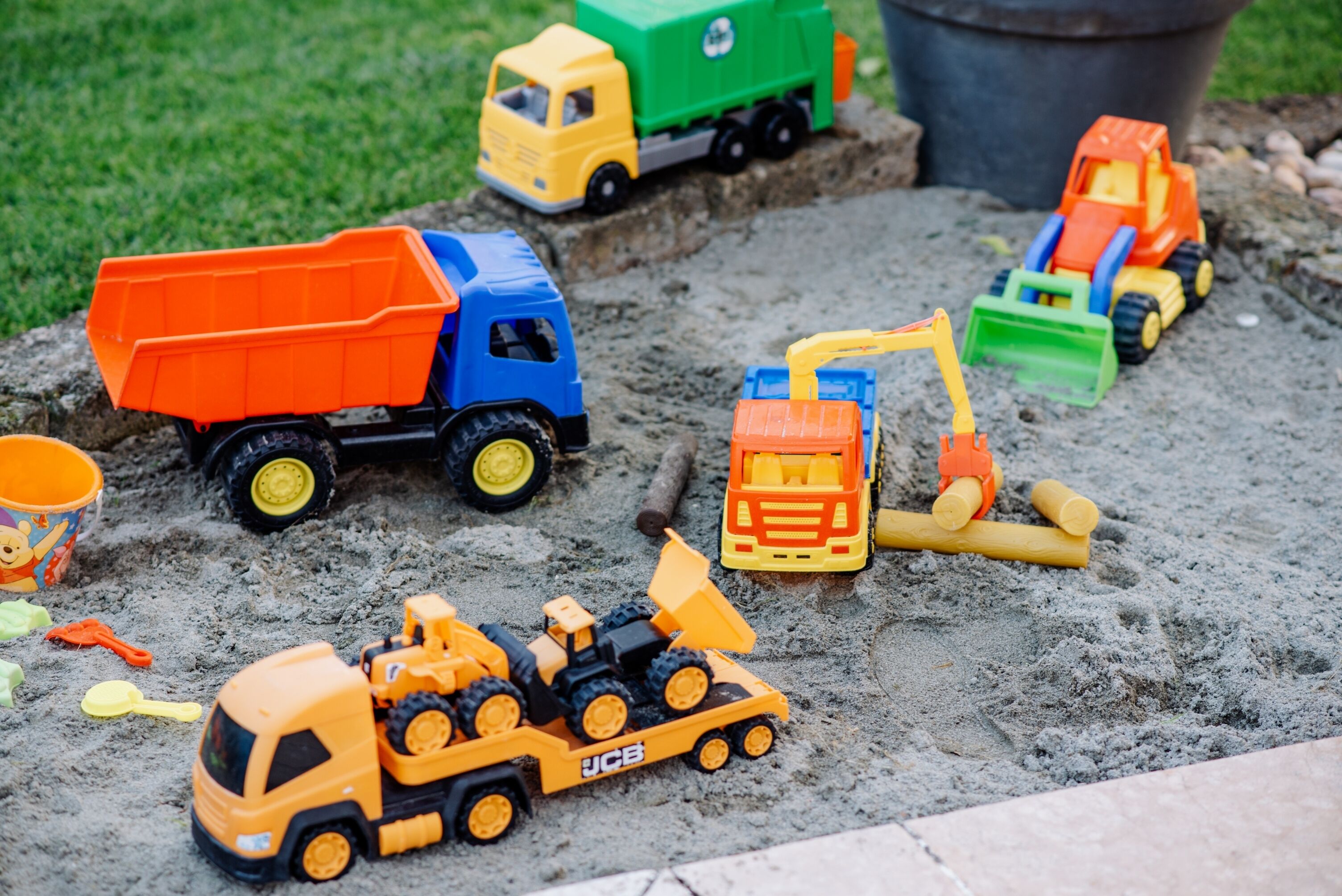 Una colección de vehículos de construcción de juguete coloridos sobre una superficie arenosa.