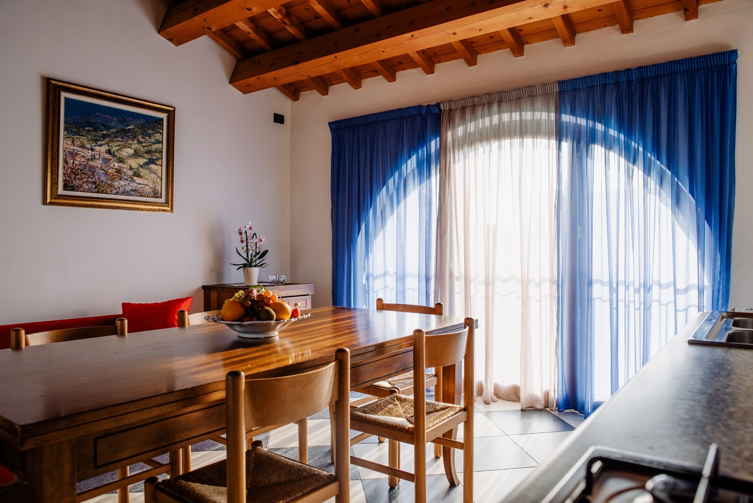 Uma sala de jantar com uma mesa de madeira, cadeiras e um vaso com flores.