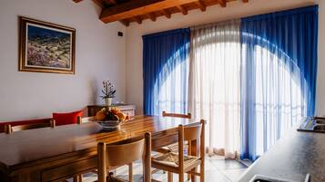 Uma sala de jantar com uma mesa de madeira, cadeiras e um vaso com flores.