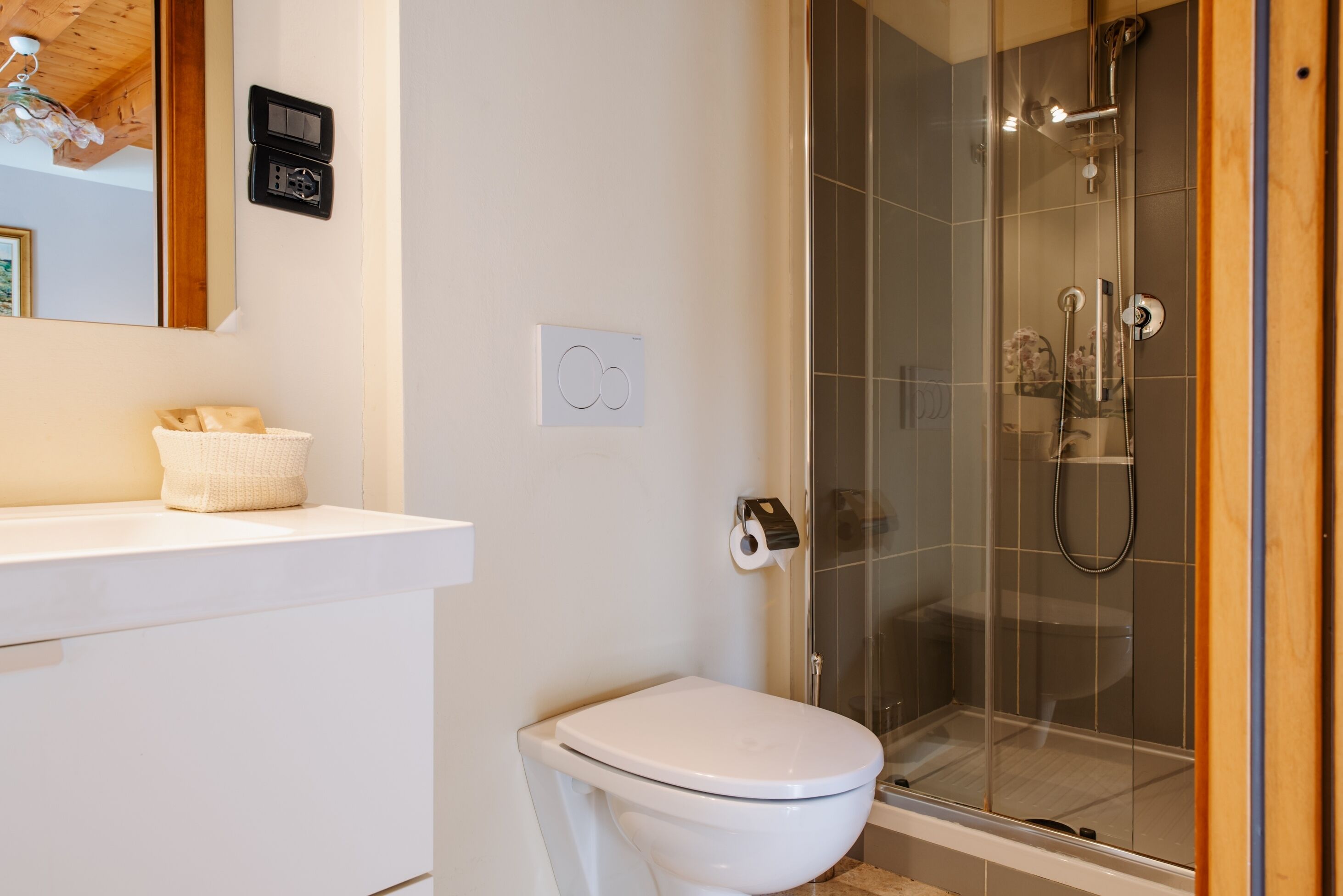 A modern bathroom with a toilet, a shower enclosure, and a sink.