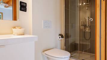 A modern bathroom with a toilet, a shower enclosure, and a sink.