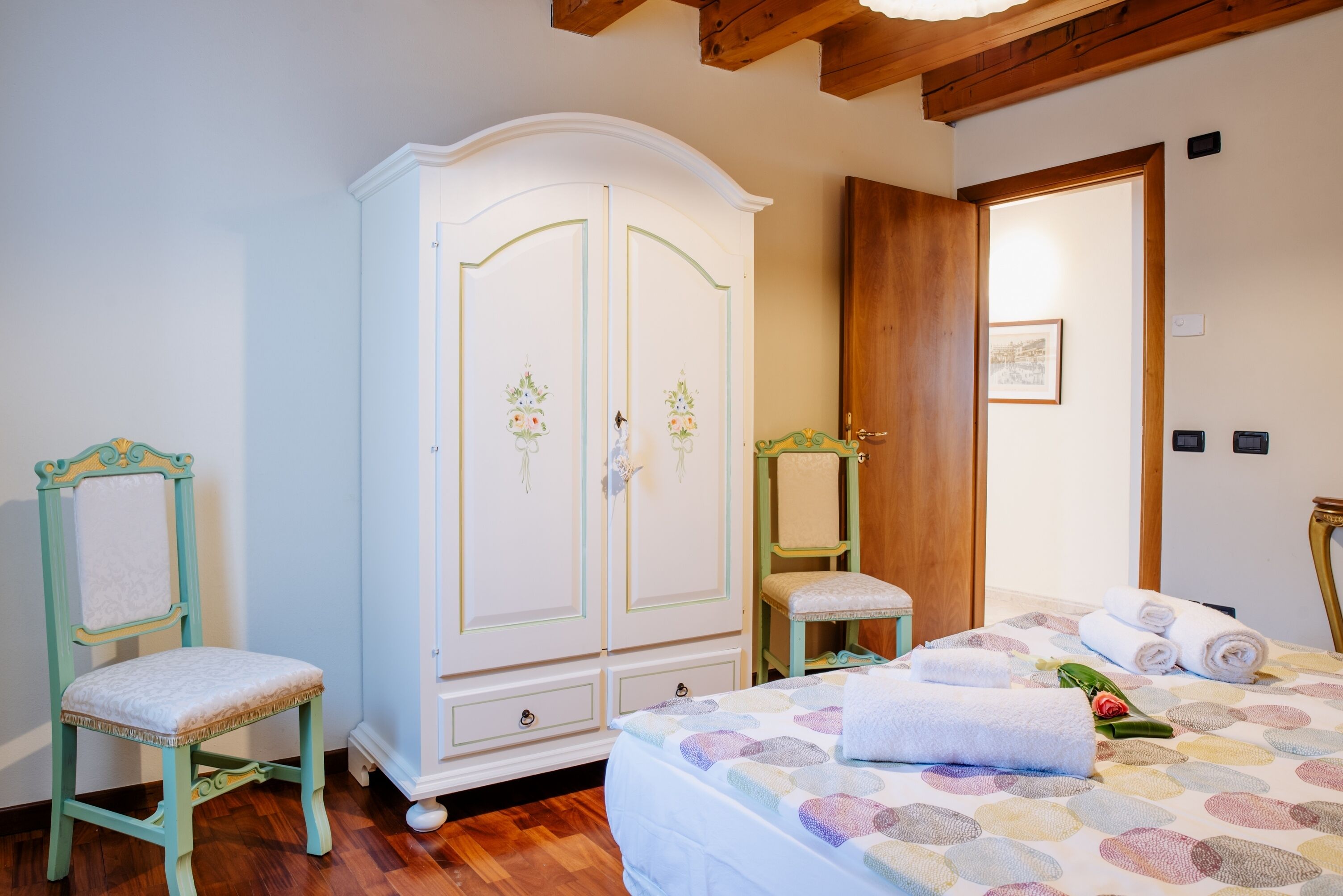 A bedroom with a bed, a wardrobe, a chair, and a small table.