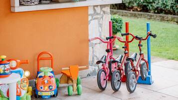 A patio area with a stone wall, a small table with toys, and a red bicycle.
