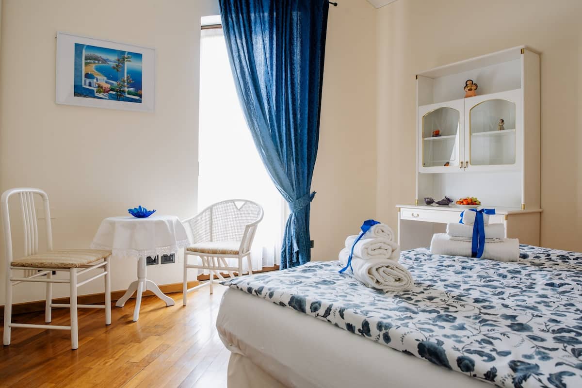 Une chambre d’hôtel comprenant un lit, un bureau, une chaise, une petite table et un placard.