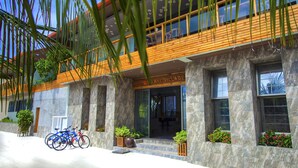 Un edificio moderno con un balcón de madera, columnas de piedra y un letrero que dice "SAANI VILLAGE".