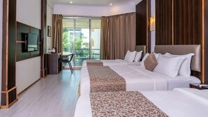 Habitación de hotel con dos camas, televisión, escritorio y balcón con vistas.