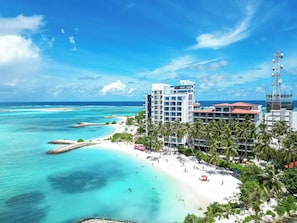 A coastal hotel with a beach, clear blue waters, and a clear sky. - Kaani Village & Spa (Maafushi)