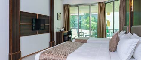 A hotel room with a large bed, a television, a desk with a chair, and a balcony with curtains.