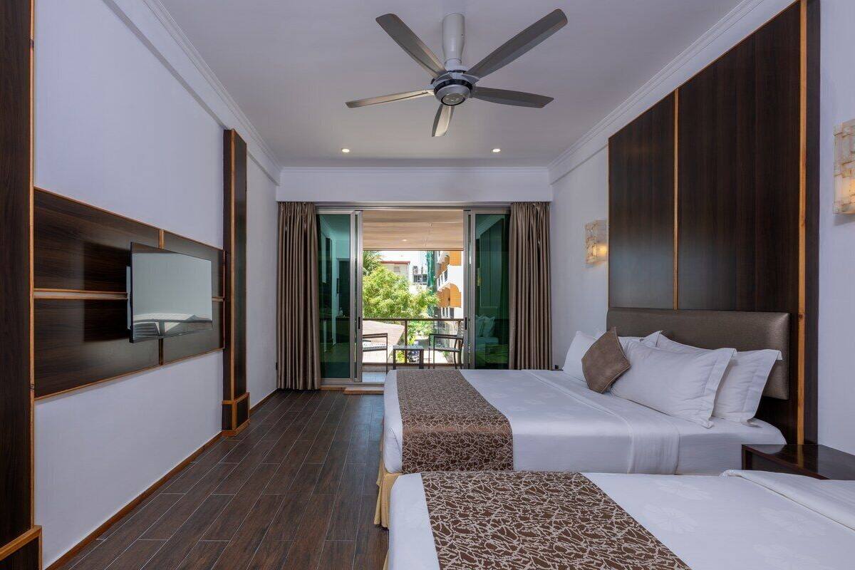 Une chambre d’hôtel avec un lit, un ventilateur de plafond, une télévision et une vue sur l’extérieur.