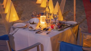 Una mesa preparada para la cena en una playa, con vista al mar.