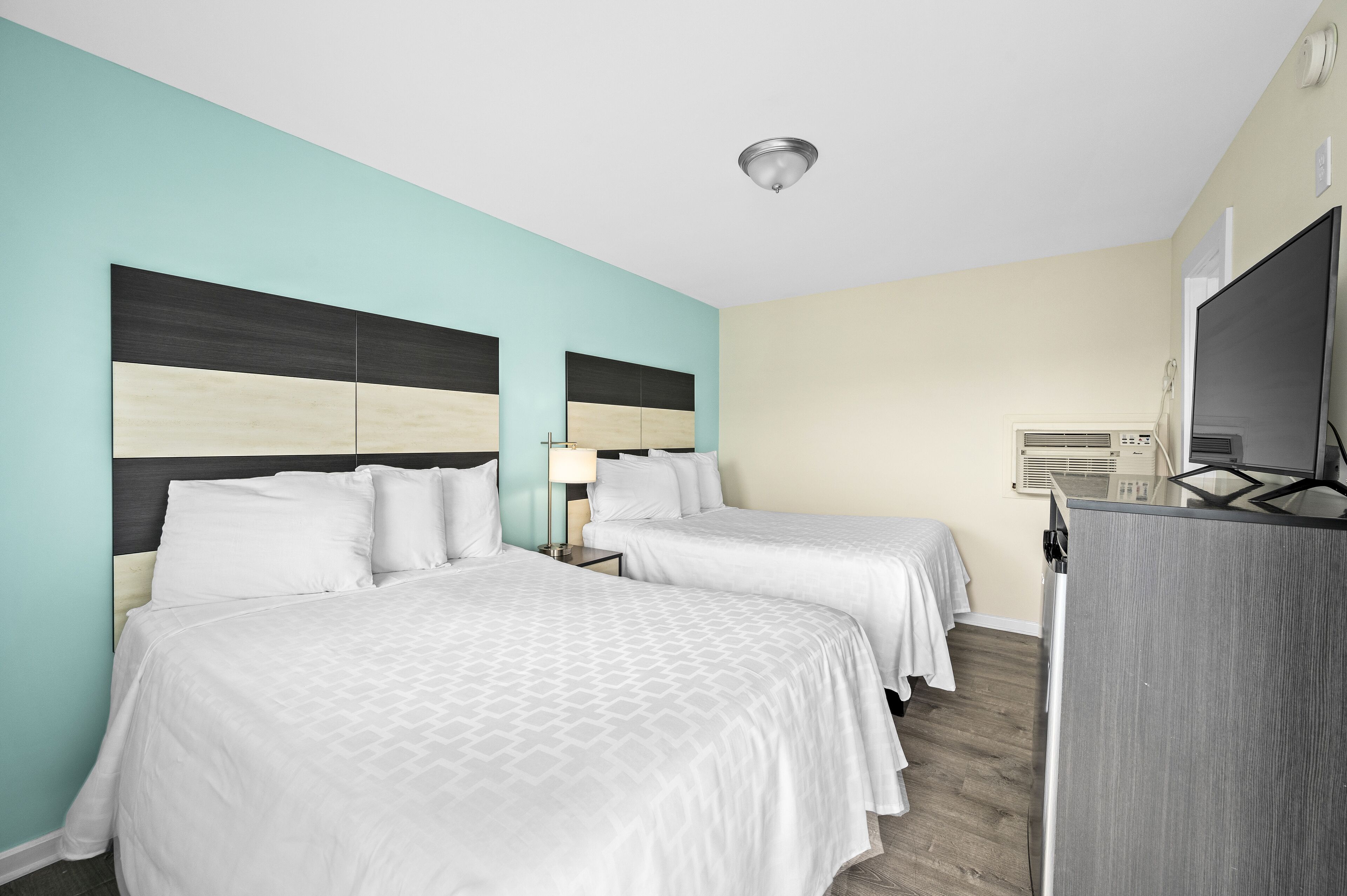 A hotel room with two beds, a TV, and a desk.