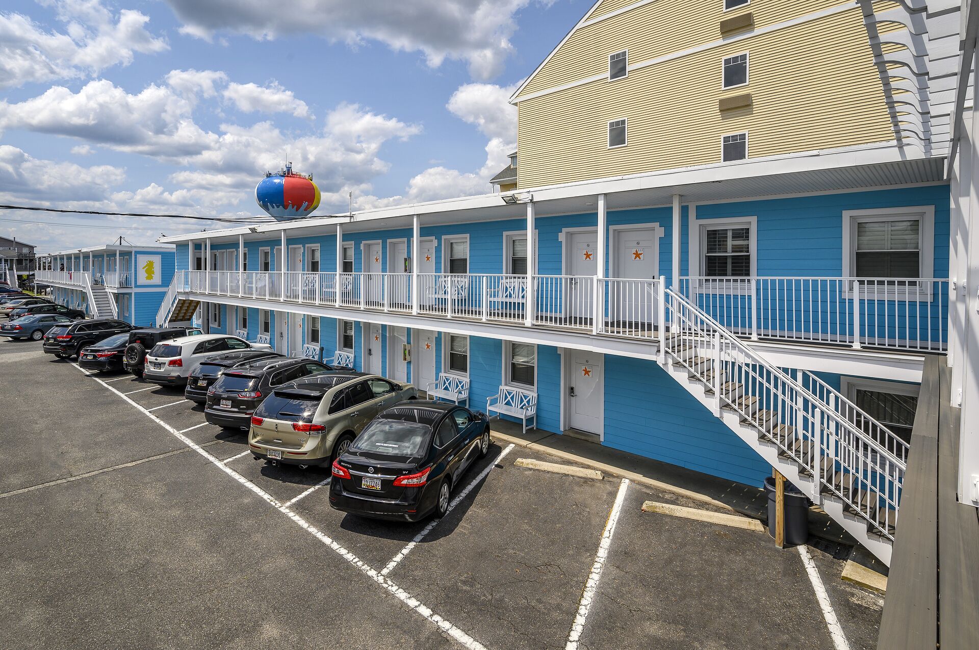 A motel with a row of parking spaces and a building with blue and white exterior walls.