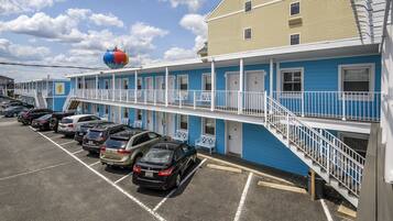A motel with a row of parking spaces and a building with blue and white exterior walls.