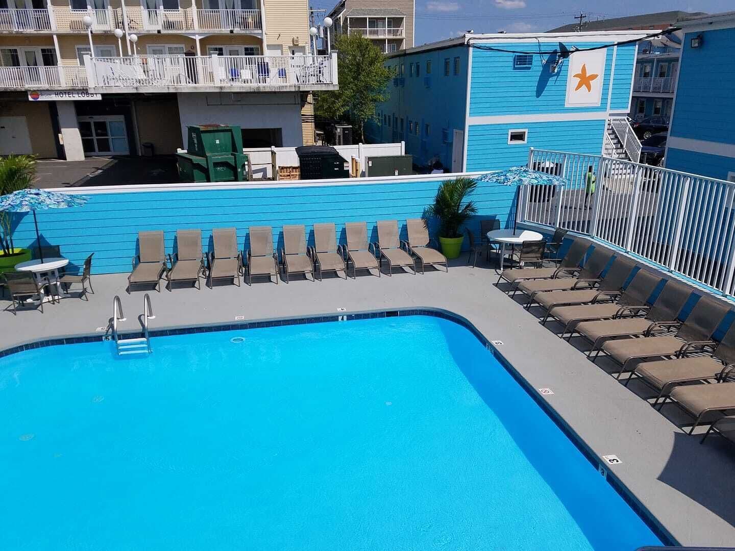 A pool area with lounge chairs and a sign for the Hotel Loquet.