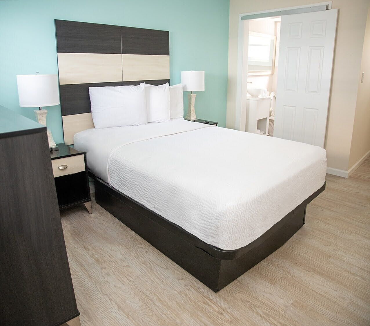 A modern bedroom with a bed, bedside tables, and a wardrobe.