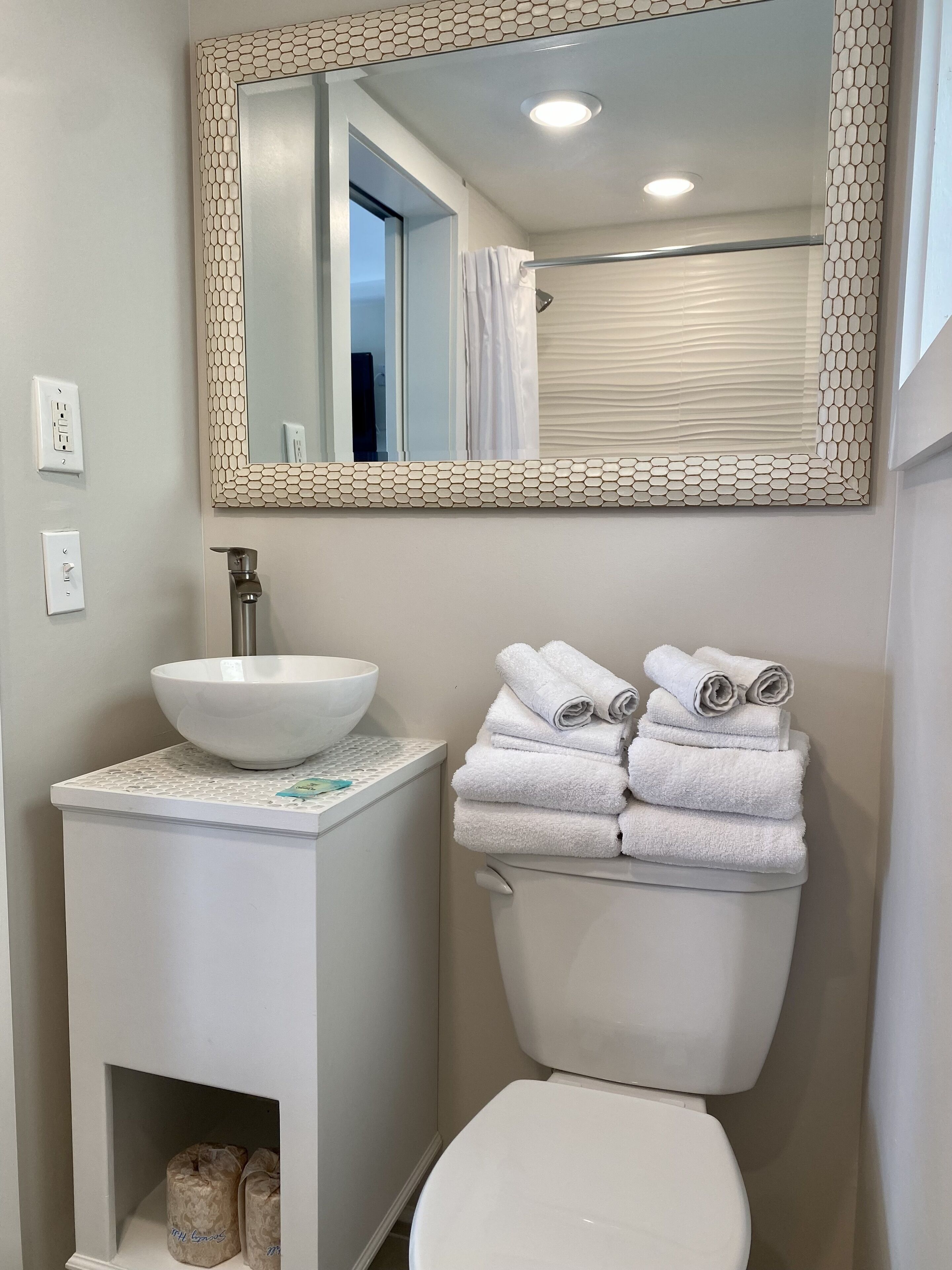 A bathroom with a white sink, a large mirror, and a toilet.