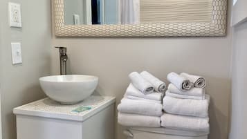 A bathroom with a white sink, a large mirror, and a toilet.