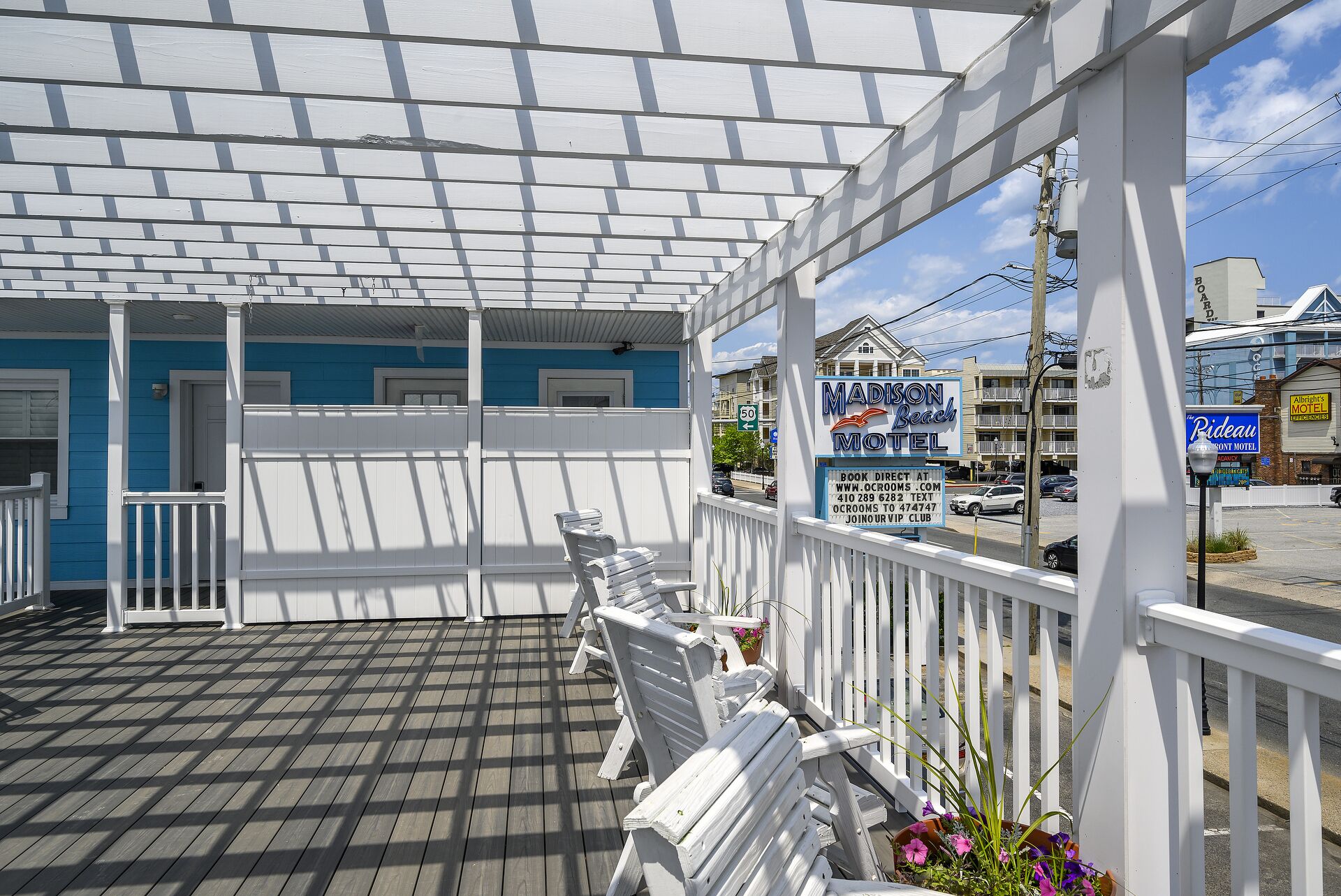 Un espacio al aire libre cubierto con barandillas blancas y una terraza de madera.