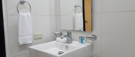 Un baño con un lavabo blanco, un espejo y dos anillas para toallas.