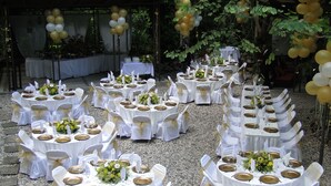 A series of round tables set up outdoors with white tablecloths, gold chargers, and white chairs with gold sashes. - La Reserve Hotel (Petionville)