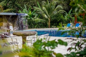 Una piscina al aire libre, sillones reclinables de piscina