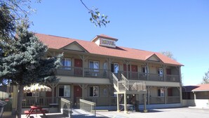 A two-story motel with a red roof and a sign that reads "Motel." There are multiple windows on each floor, and a staircase leads to the upper level.