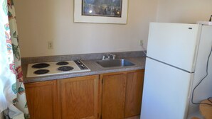A small kitchen with wooden cabinets, a white stove, a sink, and a white refrigerator.