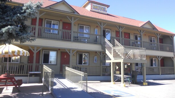 A motel with a red roof, multiple balconies, and a covered outdoor seating area.