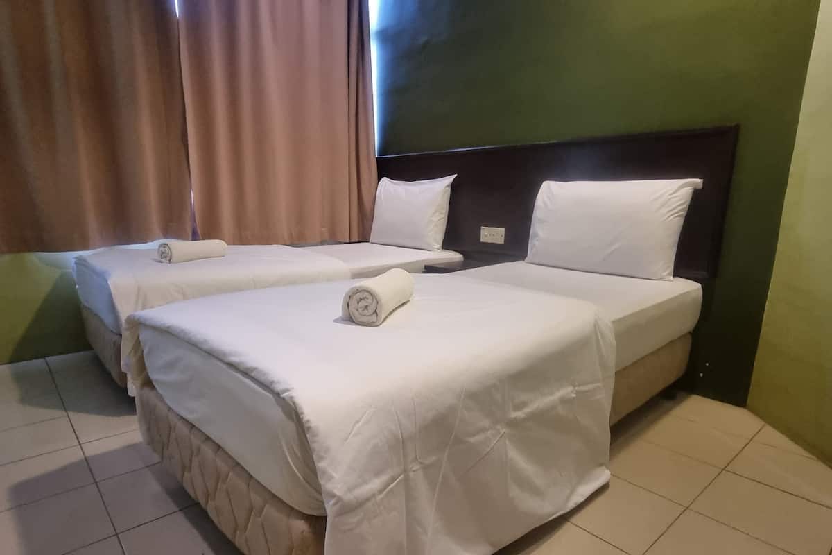 A hotel room with two beds, each with white linens and pillows, a dark headboard, and a green wall.