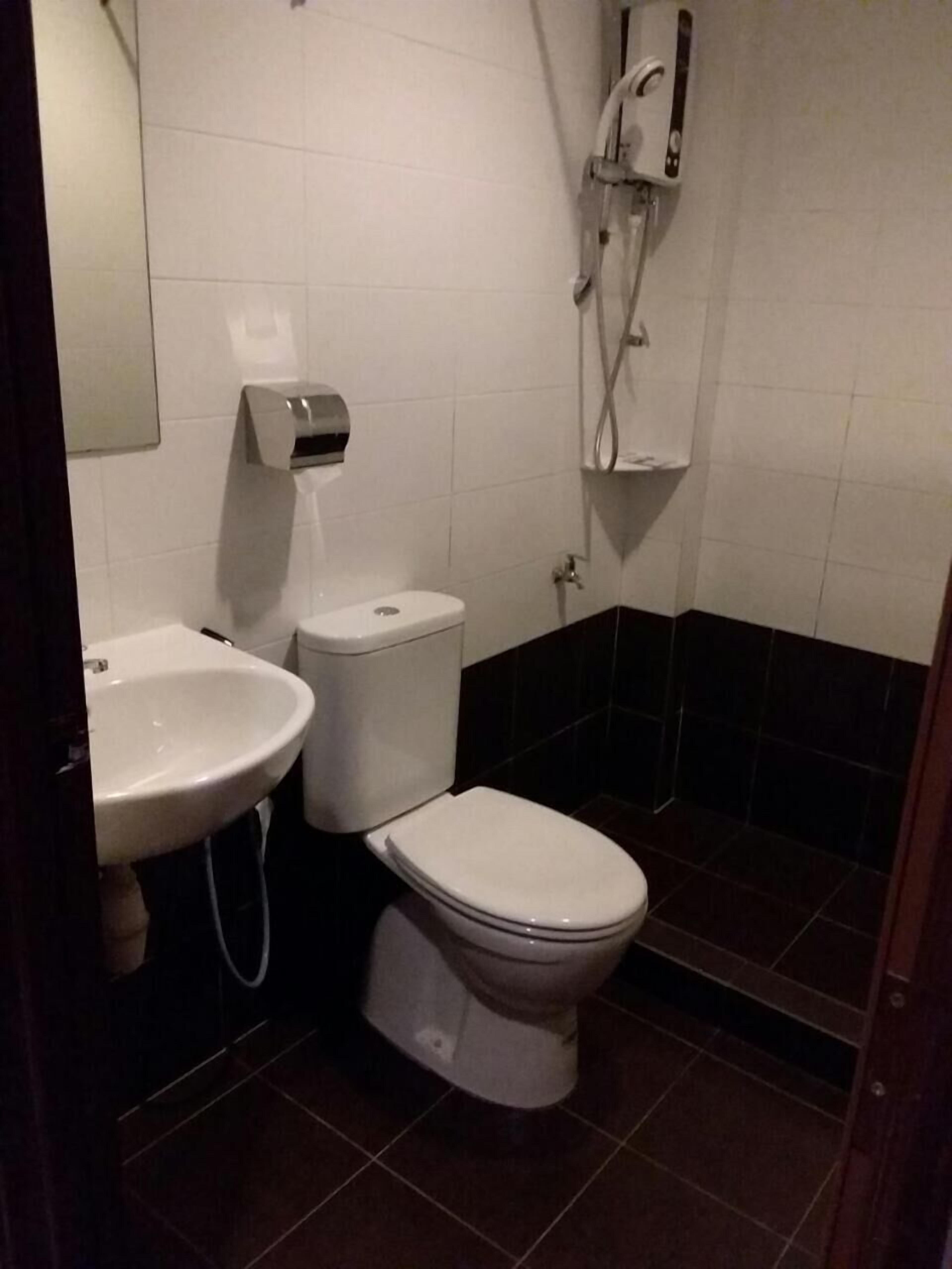 A small bathroom with a toilet, sink, and a shower unit.