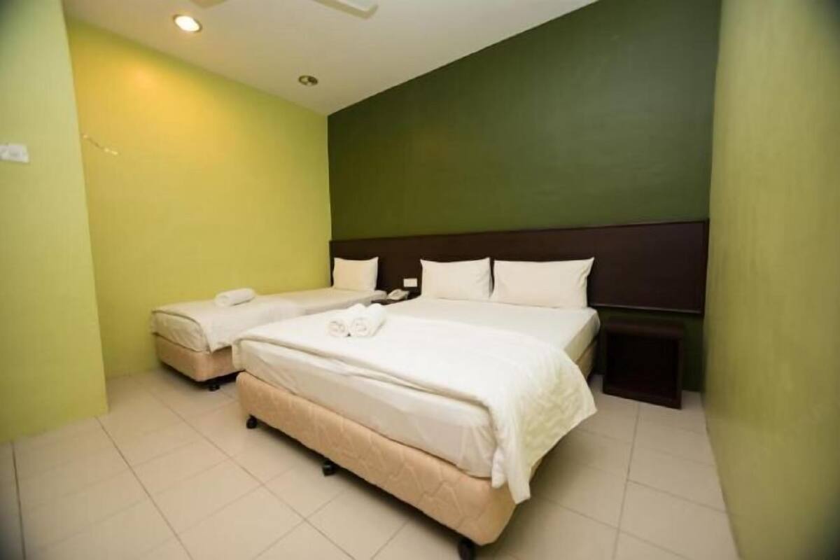 A hotel room with a large bed, a smaller bed, and a nightstand.