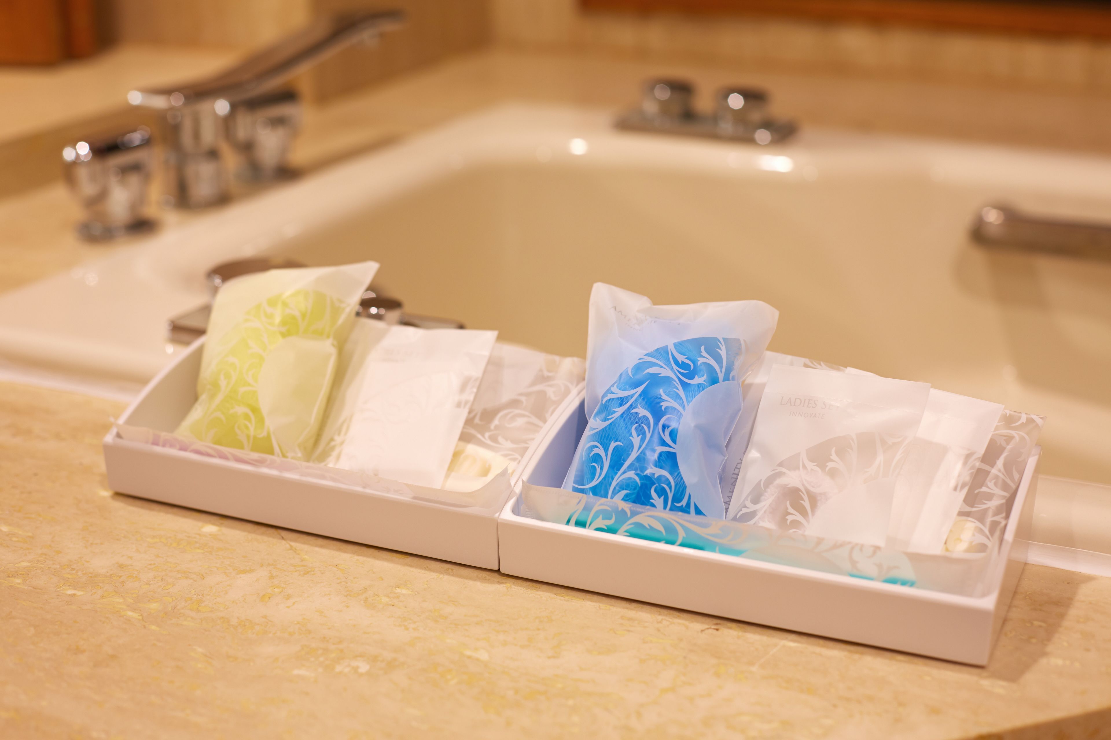 A bathroom sink with a white tray holding two tissue boxes.