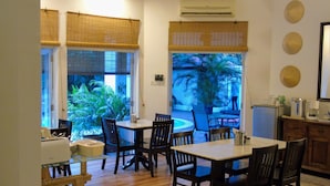 Un comedor con mesa y sillas, un equipo de aire acondicionado y vista a un jardín por la ventana.