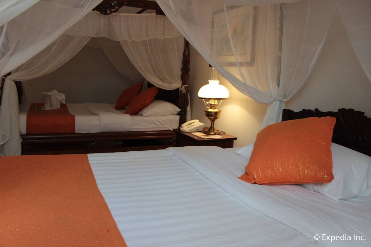 A hotel room with a bed, a nightstand, a lamp, and a telephone.