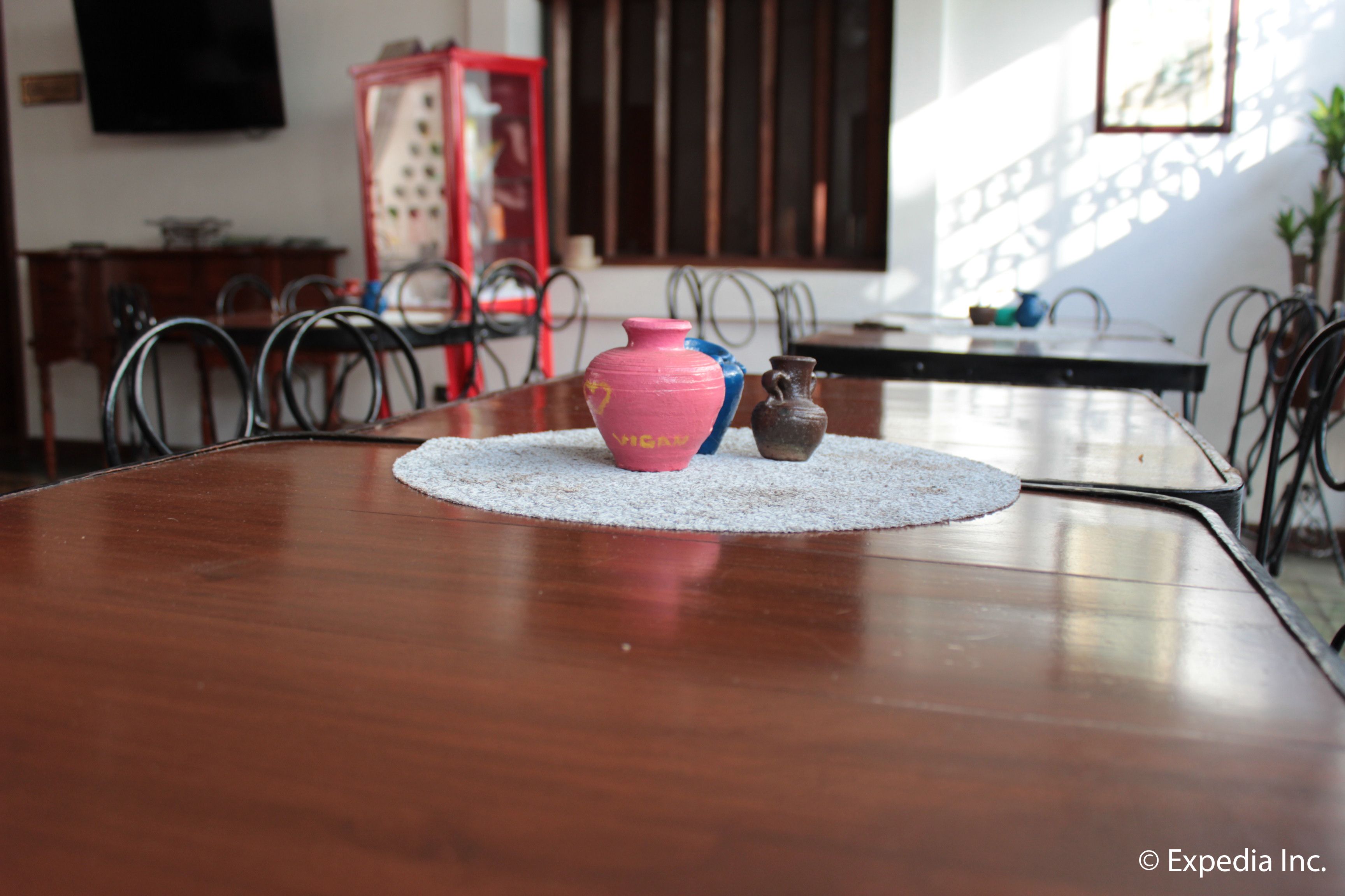 Een eettafel met een placemat, een roze vaas en een kleine bruine vaas.