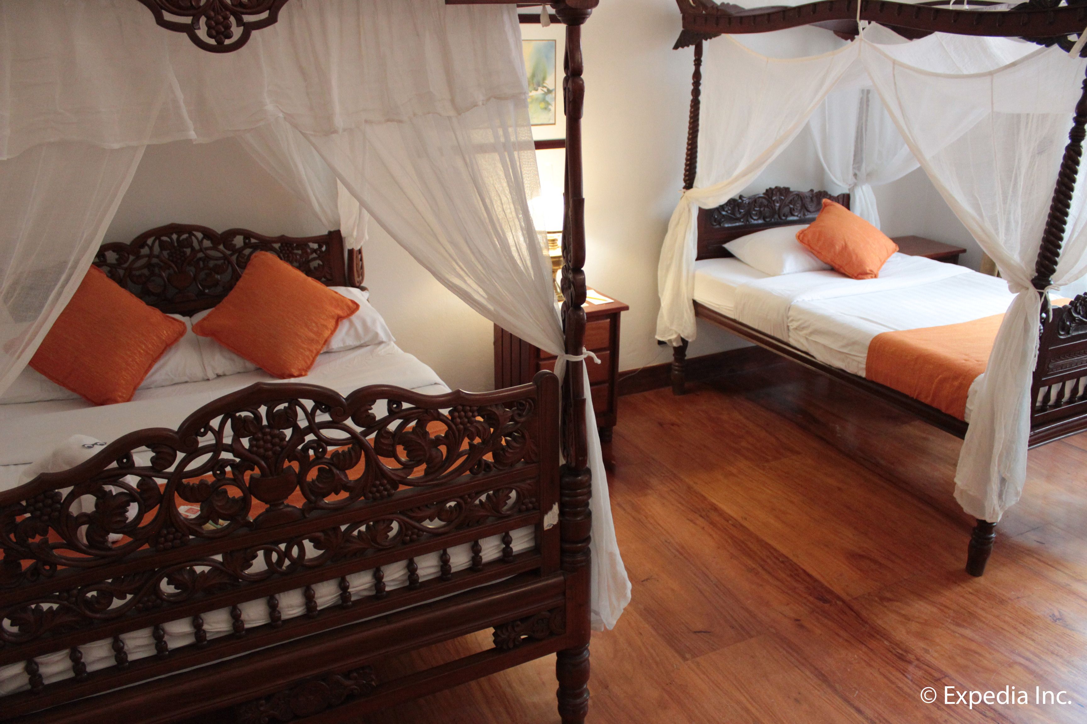A traditional four-poster bed with a canopy, two pillows, and a nightstand.