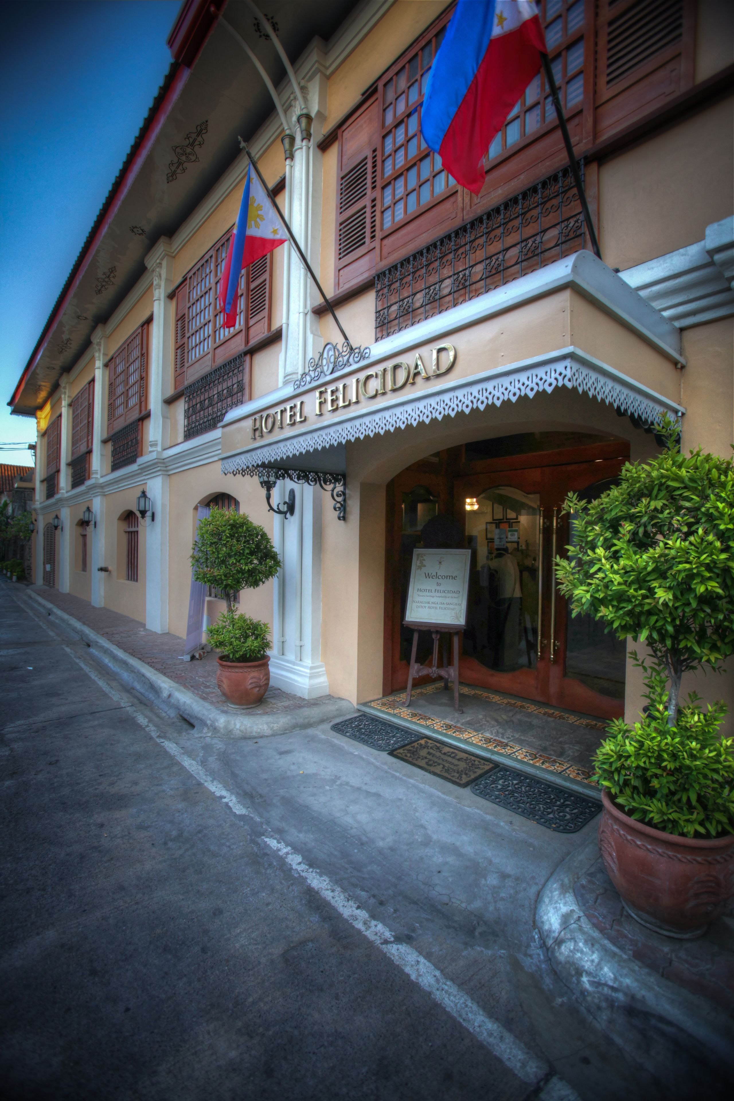 A hotel facade with the name "HOTEL FELICIDAD" and two flags.