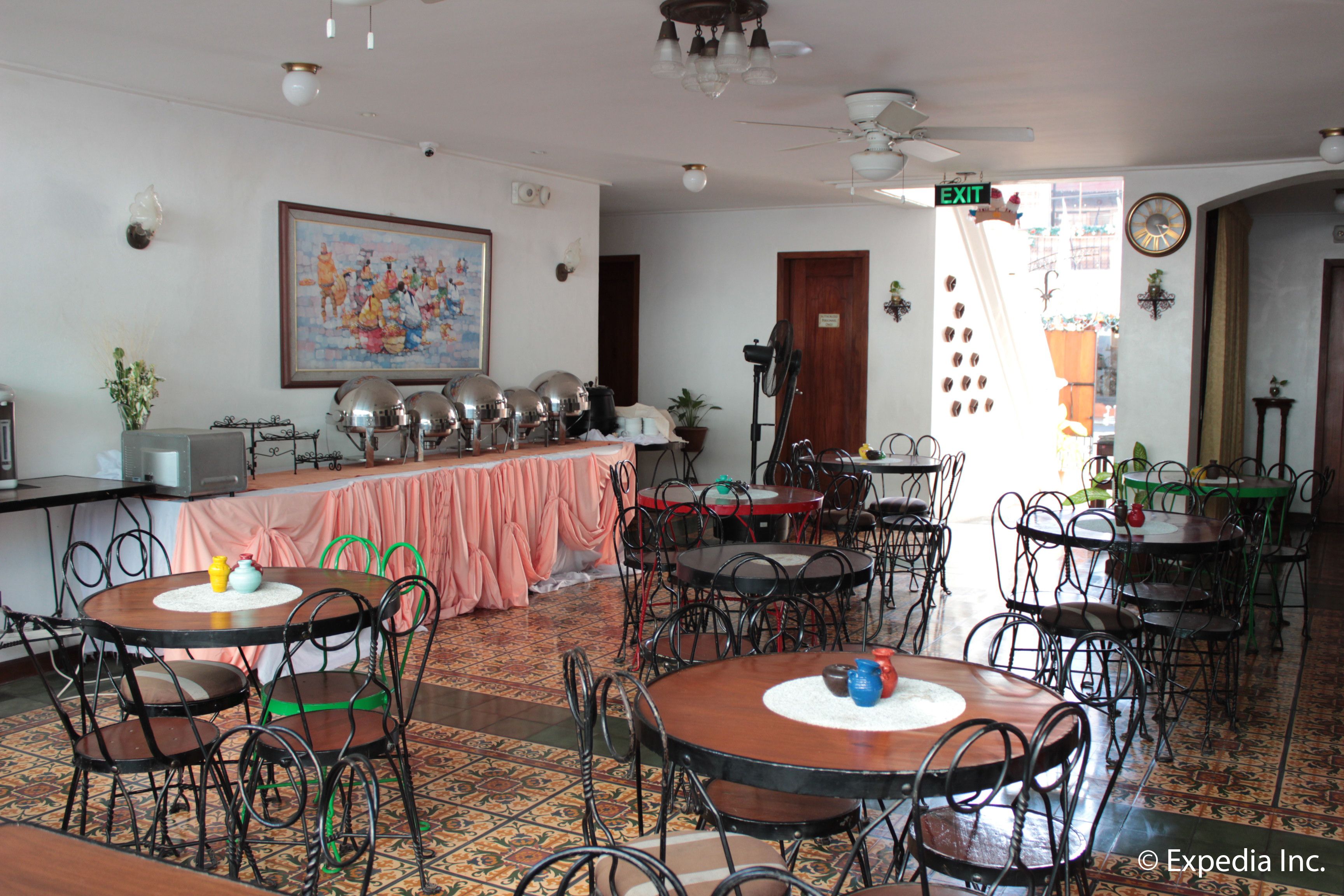 A dining area with multiple tables and chairs, a ceiling fan, and a clock on the wall.