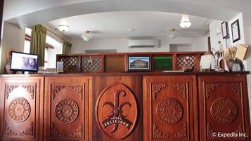 A reception desk with a clock, air conditioning unit, and framed pictures.