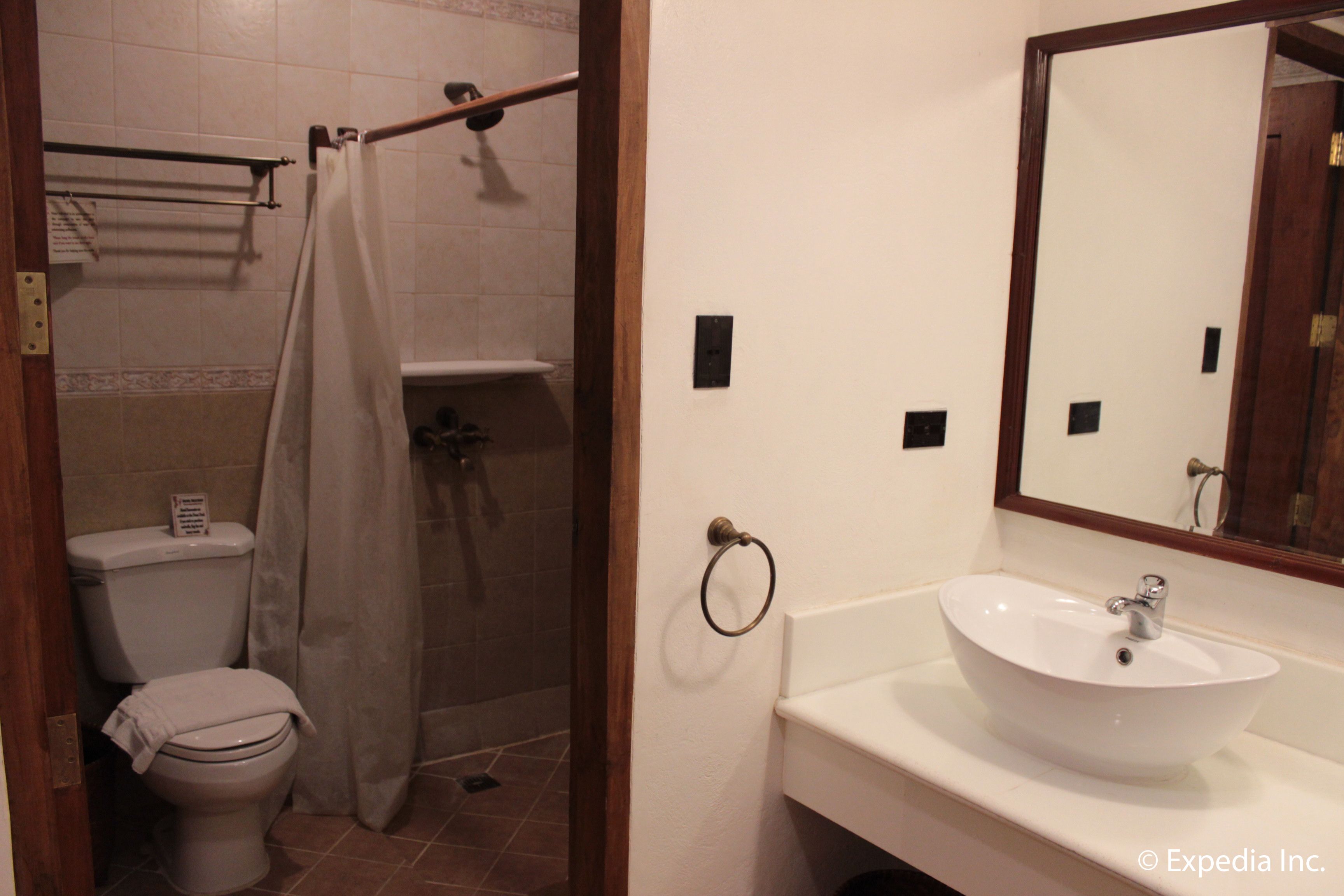 A bathroom with a toilet, shower, sink, and mirror.