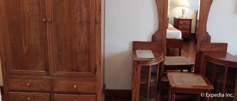A wooden wardrobe, a mirror, and a small table with chairs in a room.