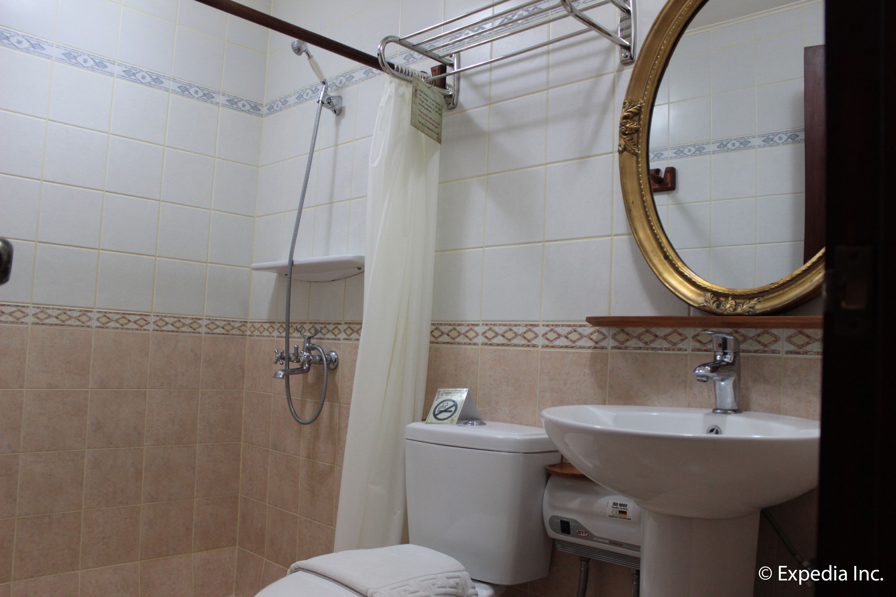 A bathroom with a shower, toilet, sink, and a mirror.